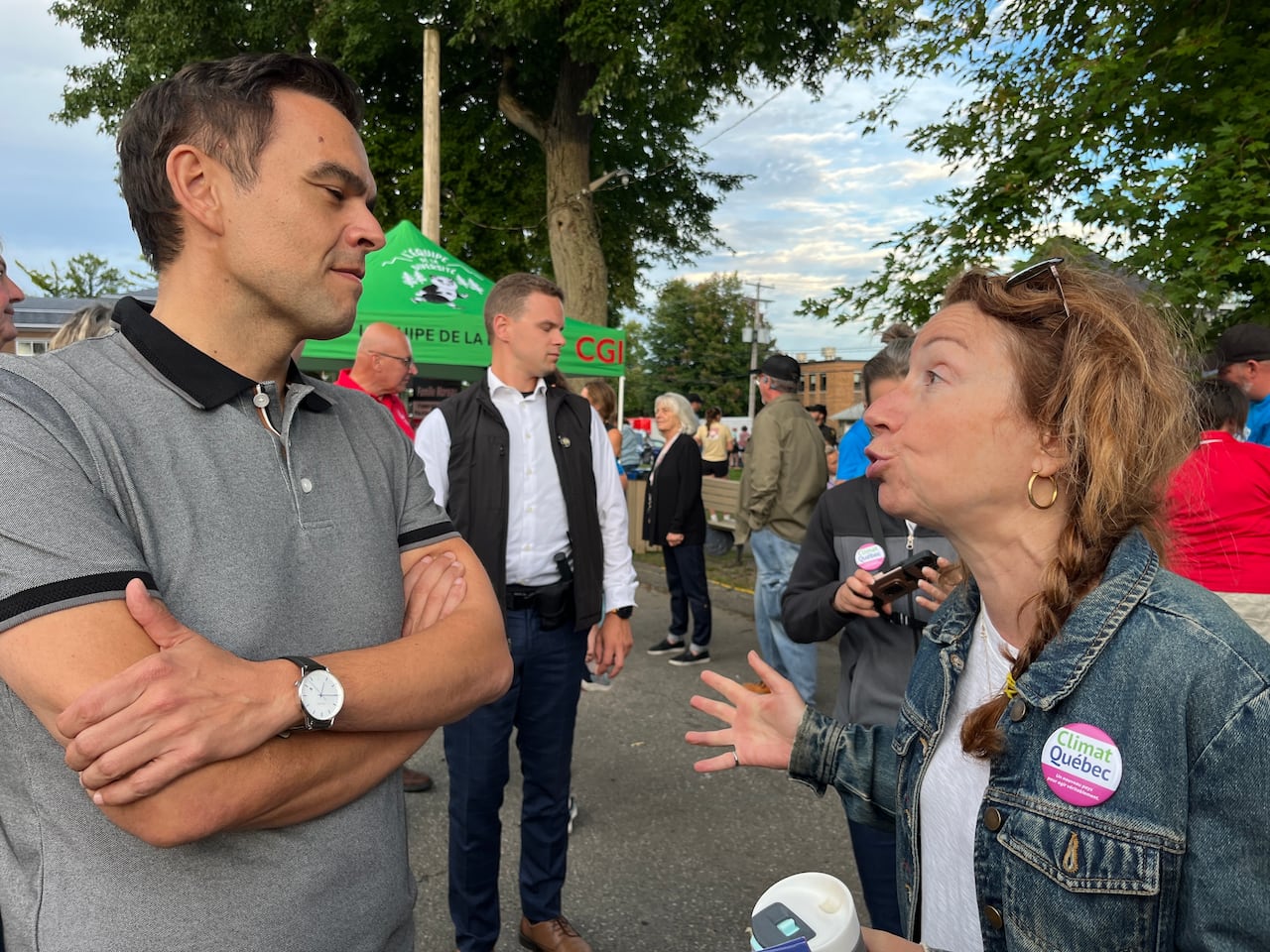 A man and a woman speak to each other outside in front of boothing tents.