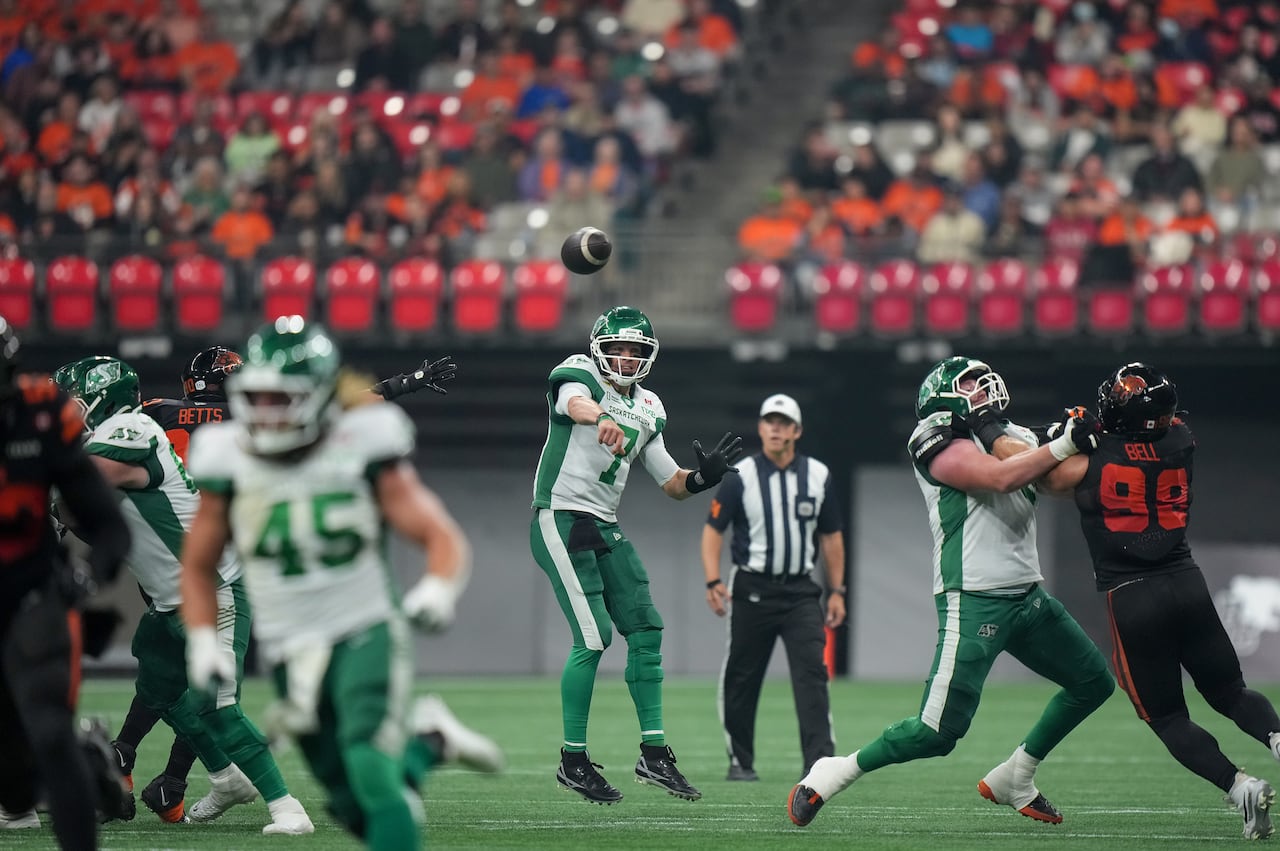 A man in a football uniform throws a football forward toward the camera.