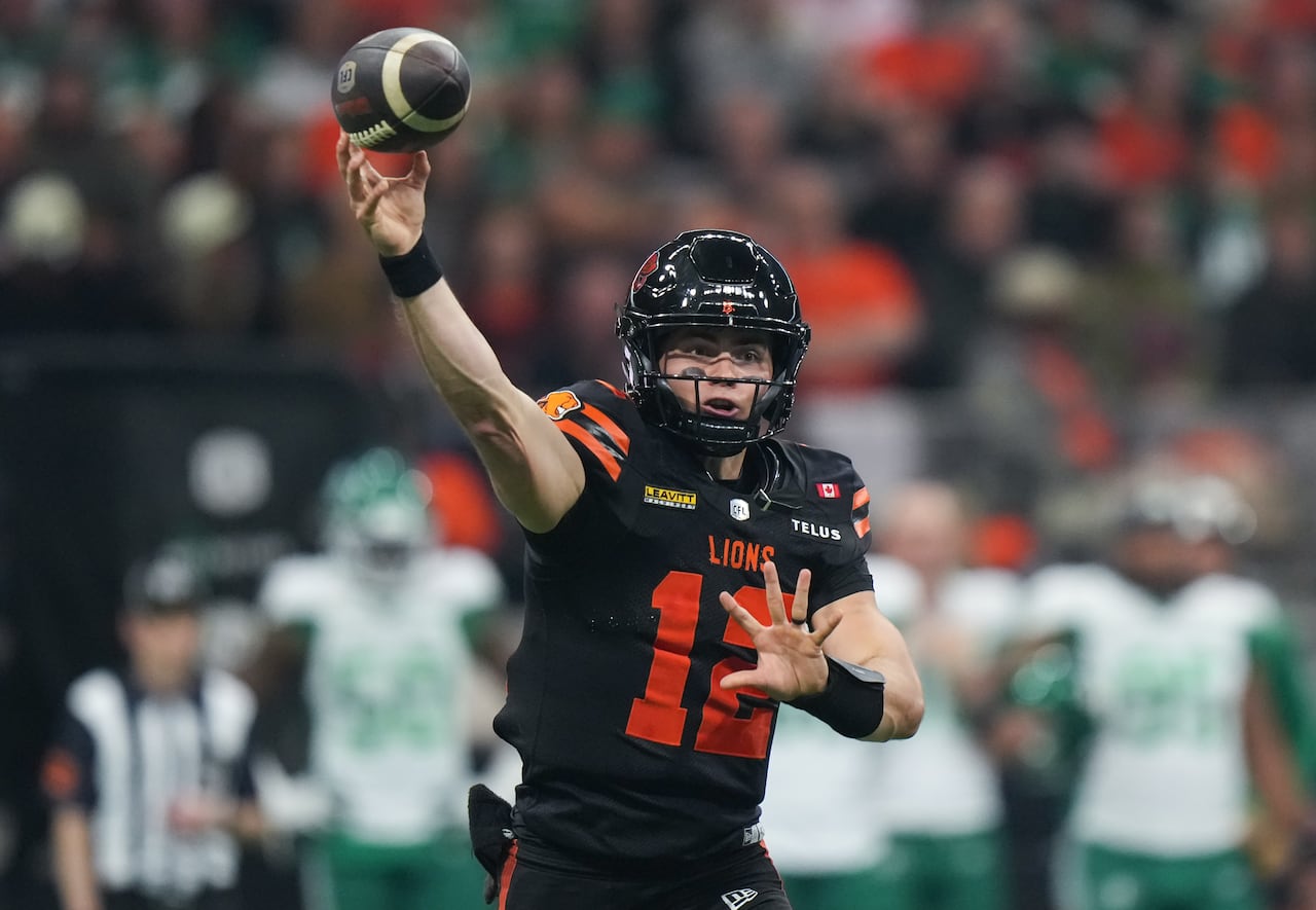 A man reaches his arm up, almost touching a football.