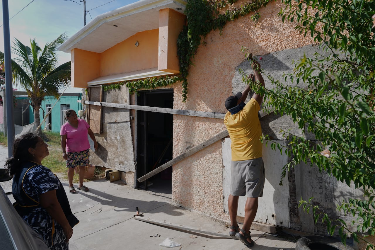 A man boards up a house's windows.