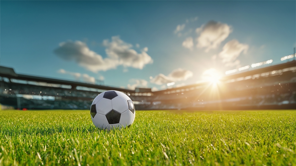 american soccer ball on grassy field in stadium on a sunny day.