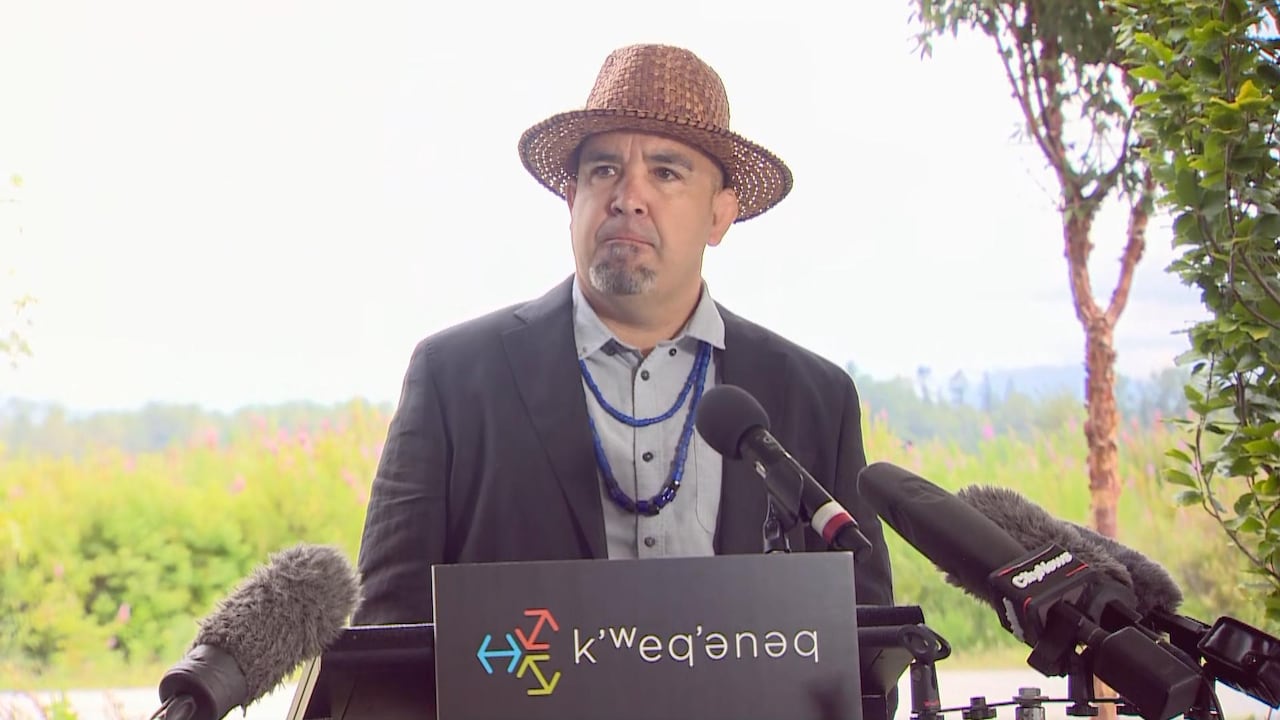 A man wearing a straw hat and suit speaks at a podium.