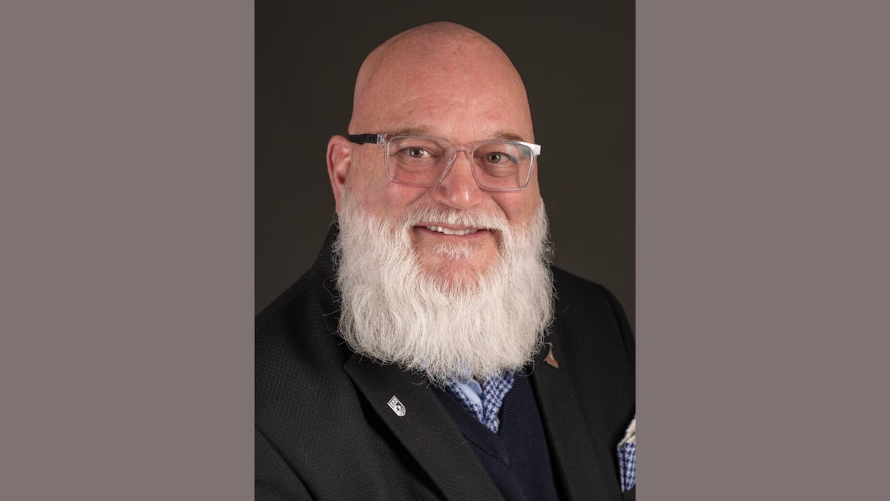 A headshot of a person with a white beard and glasses.