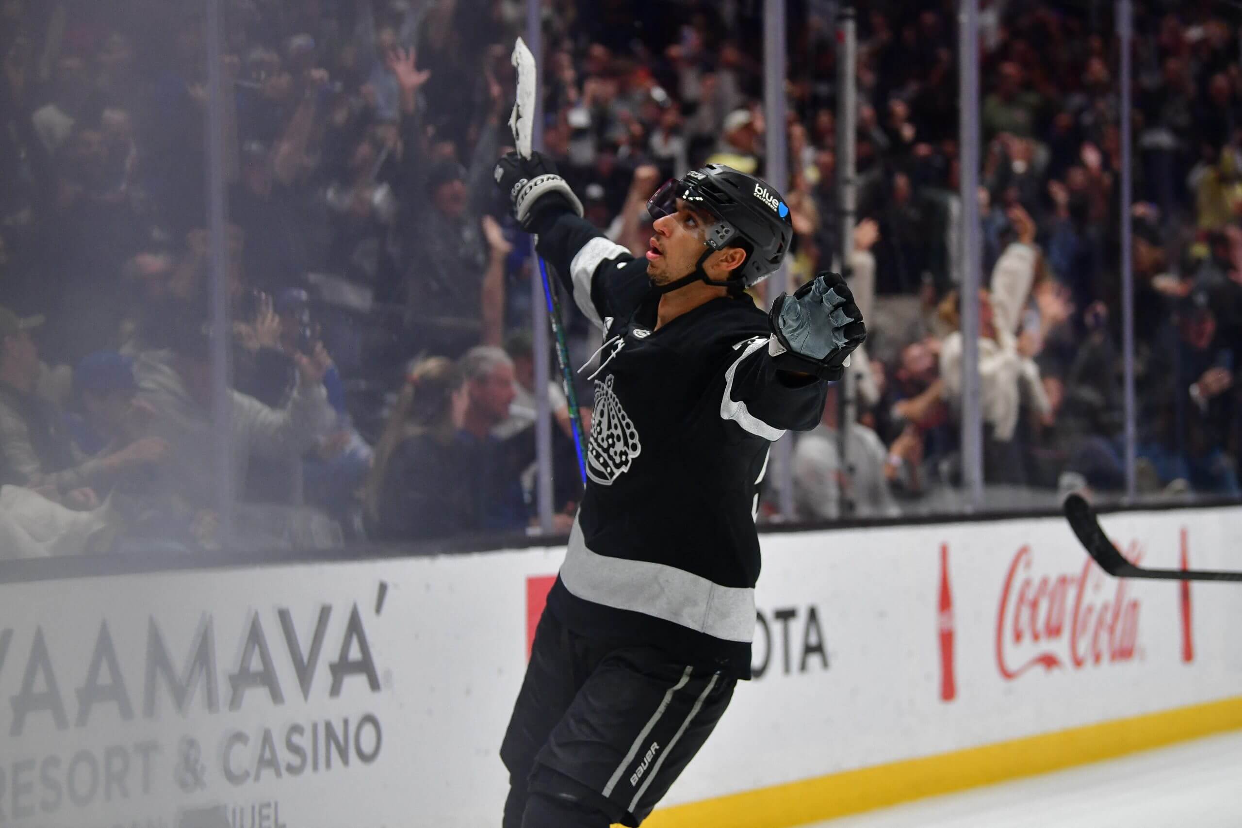 Quinton Byfield raises both arms to the side in celebration after scoring a goal.