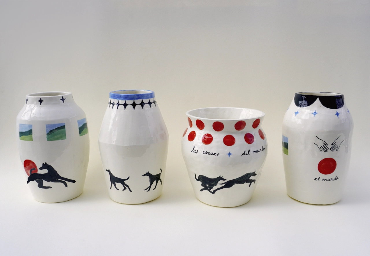 Four white ceramic vessels decorated with hand-painted black silhouettes of dogs, red circular motifs and blue line details, each with text inscriptions