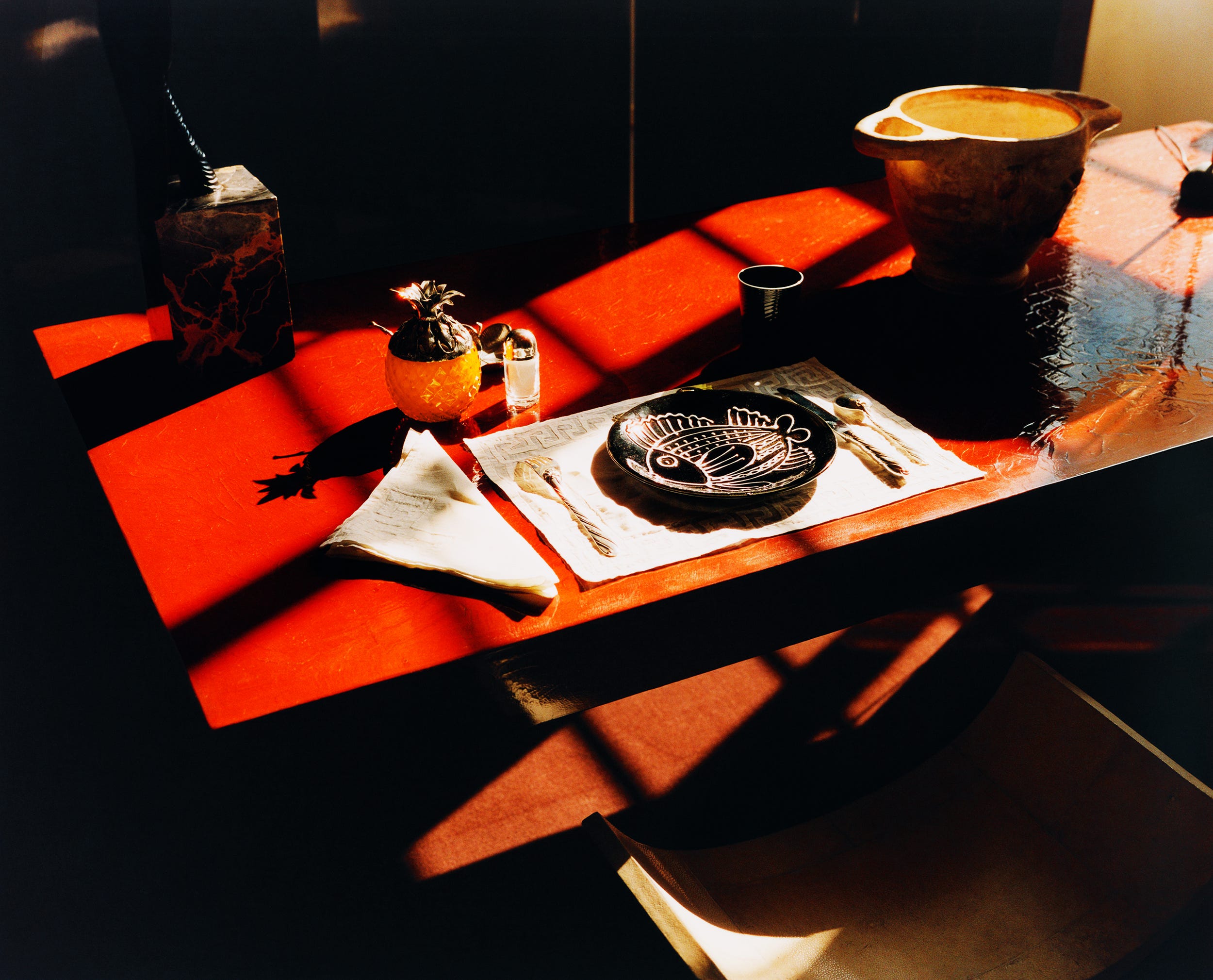 A beautifully set dining table featuring a fish plate and decorative items, illuminated by warm sunlight.