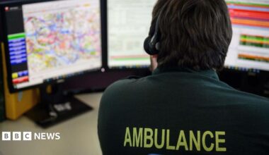 An emergency services call handler sitting at a desk with a headset on taking a call
