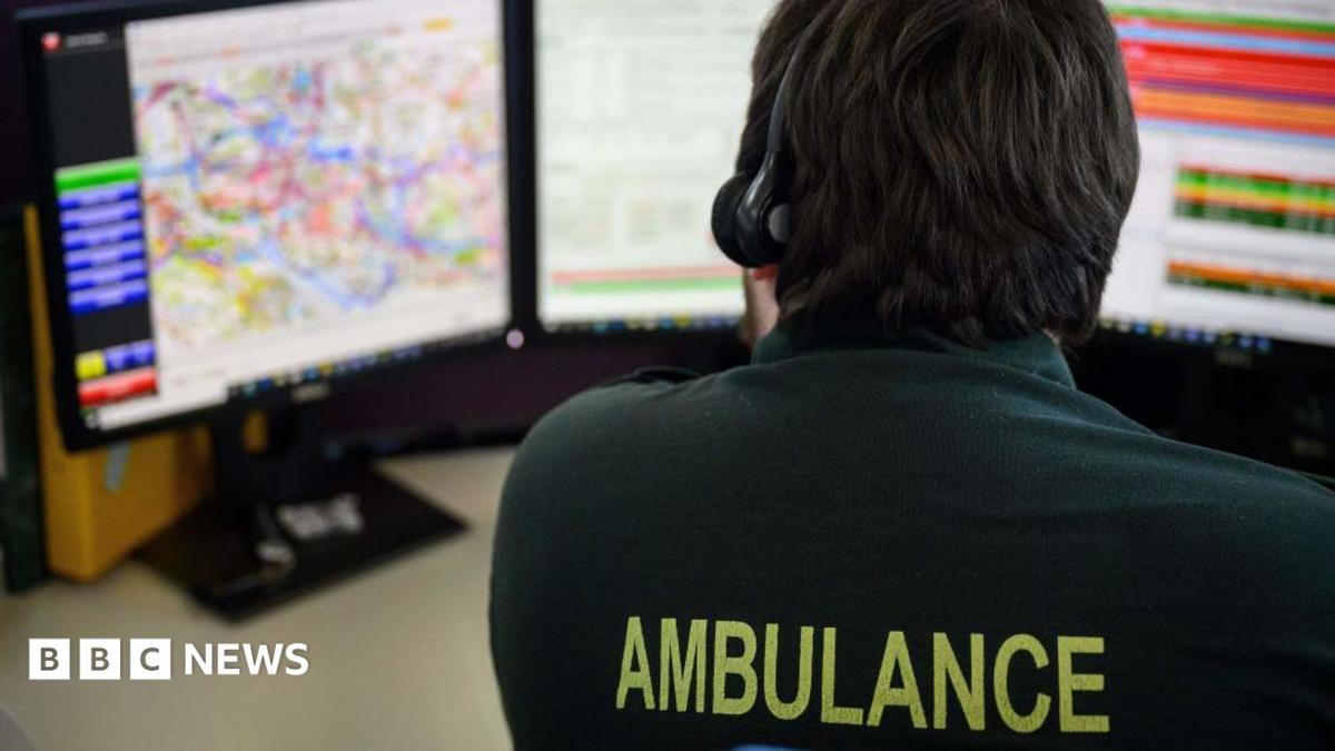 An emergency services call handler sitting at a desk with a headset on taking a call