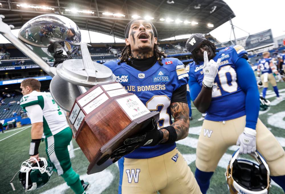 JOHN WOODS / THE CANADIAN PRESS
Winnipeg Blue Bombers’ Trey Vaval (23) and Nuer Gatkuoth (40) celebrate a win over the Saskatchewan Roughriders with the Banjo Bowl trophy following CFL action in Winnipeg on Saturday.