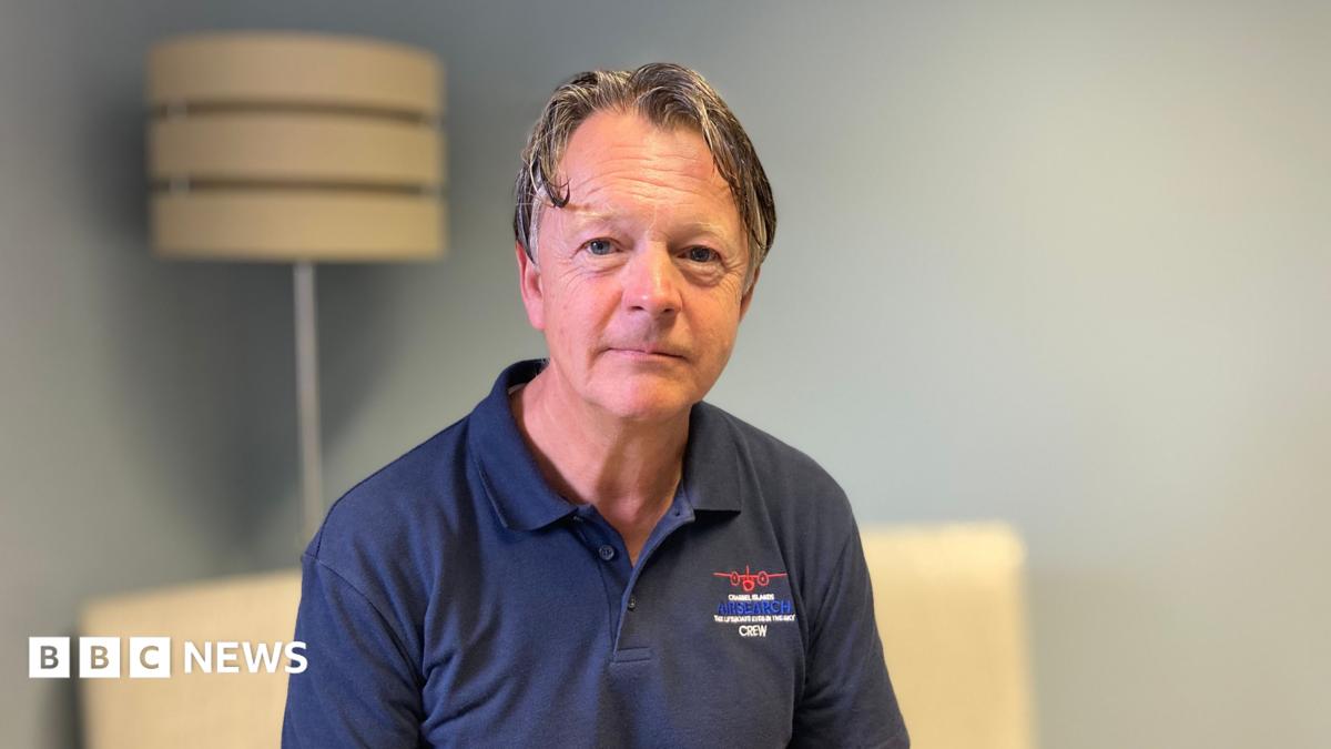 A man with grey hair wearing a navy blue polo shirt