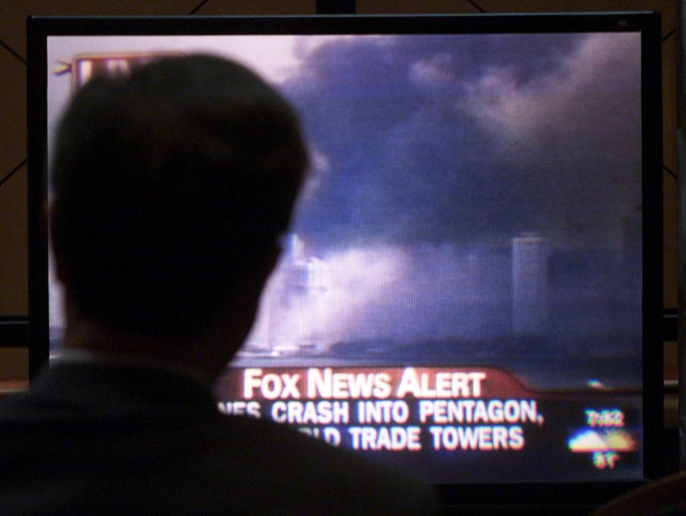 A man is silhouetted as he watches a television on Sept. 11, 2001 in Edmonton, showing smoke covering the downtown area of New York City after two separate planes crashed into the World Trade Center. (CP PHOTO/Adrian Wyld)