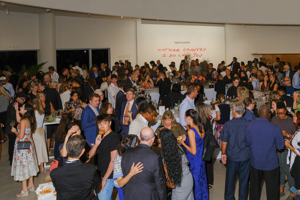 Taryn Simon | “Father Country I Do Love You” 2026 Opening Reception Crowd of people mingling at an indoor event with a bar and art displayed on the wall.