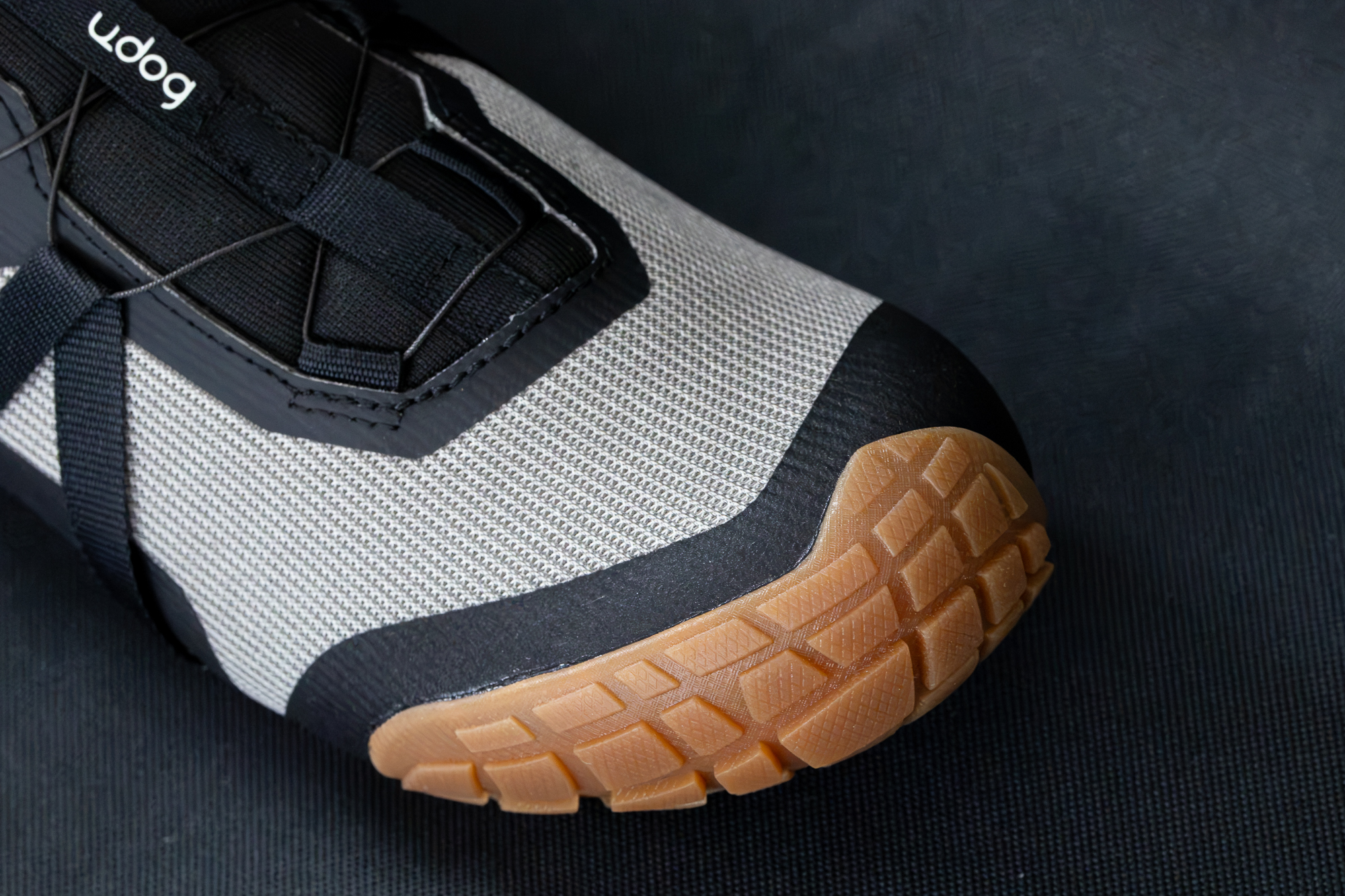 Close up of a grey shoe showing the big rubber toe bumper and knit fabric