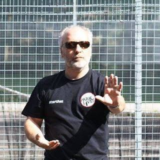 man wearing a black tshirt and dark glasses facing the camera doing a tai chi move