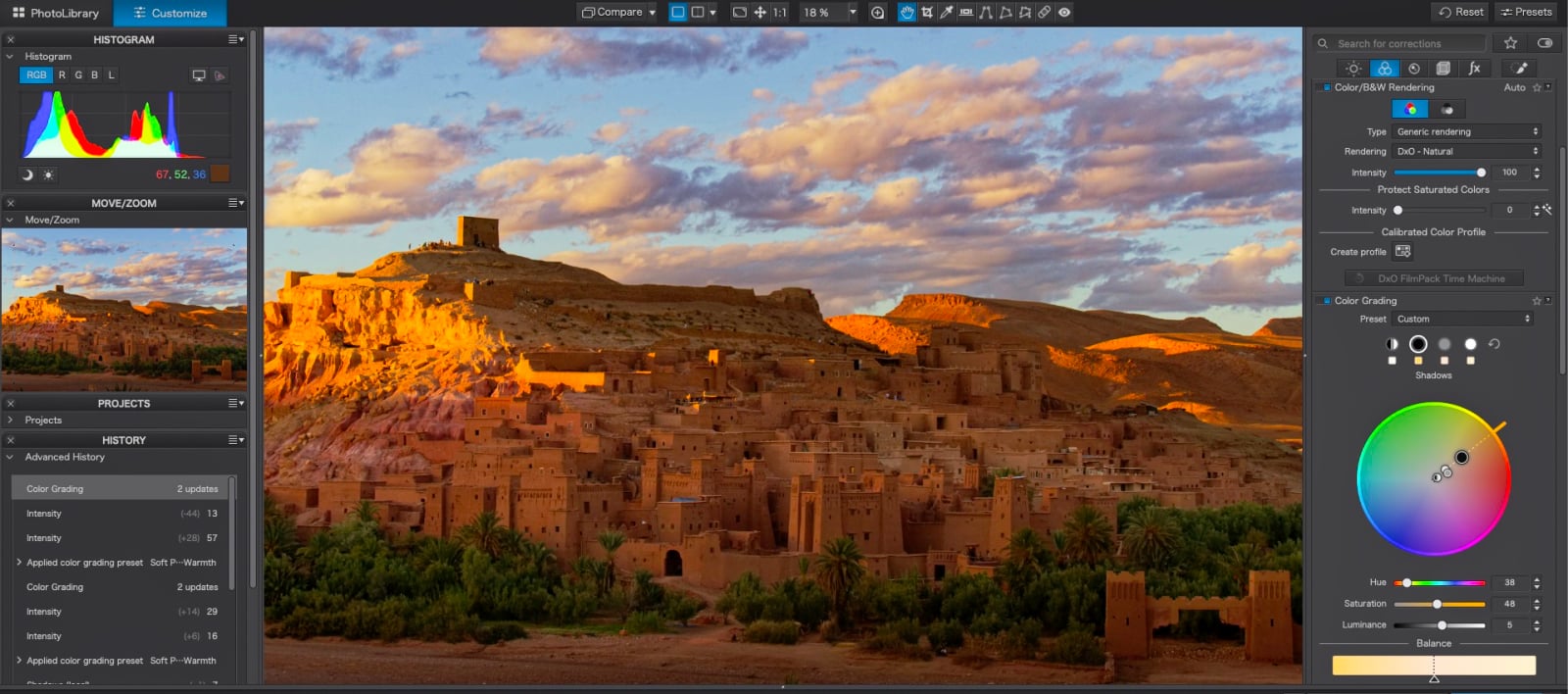 A computer screen displays a photo editing interface showing a landscape of a desert village at sunset, with a color grading wheel and histogram panels visible.