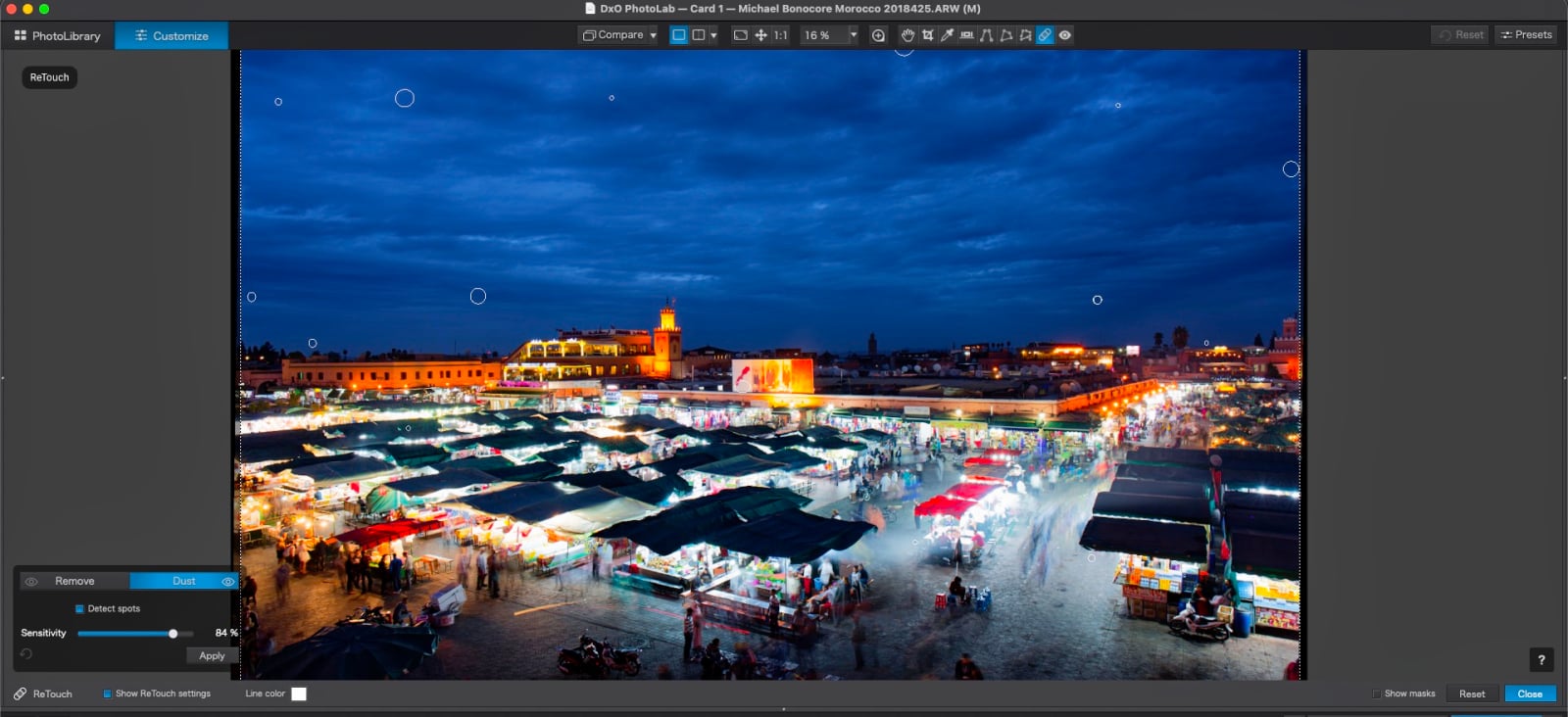 A software interface displays a night market scene with several circular retouching markers overlaid on the sky and stalls.