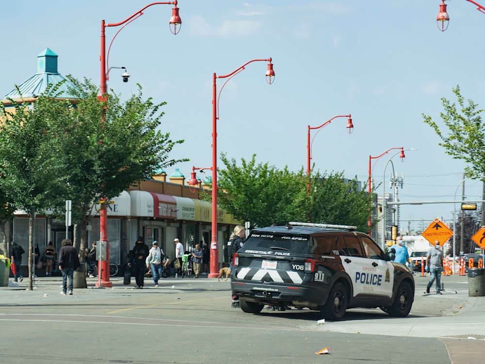 A black and white police car on a downtown street.