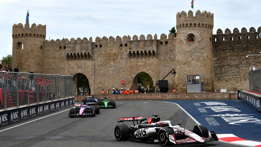 F1 cars driving around the Baku Street Circuit with the Maiden Tower in the background.