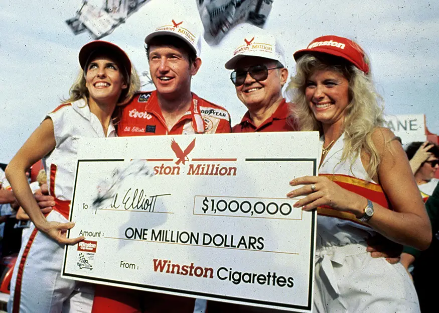 Bill Elliott celebrates his 1985 Southern 500 victory at Darlington Raceway while holding the $1 million Winston Million cheque after winning three of NASCAR’s four crown-jewel races.