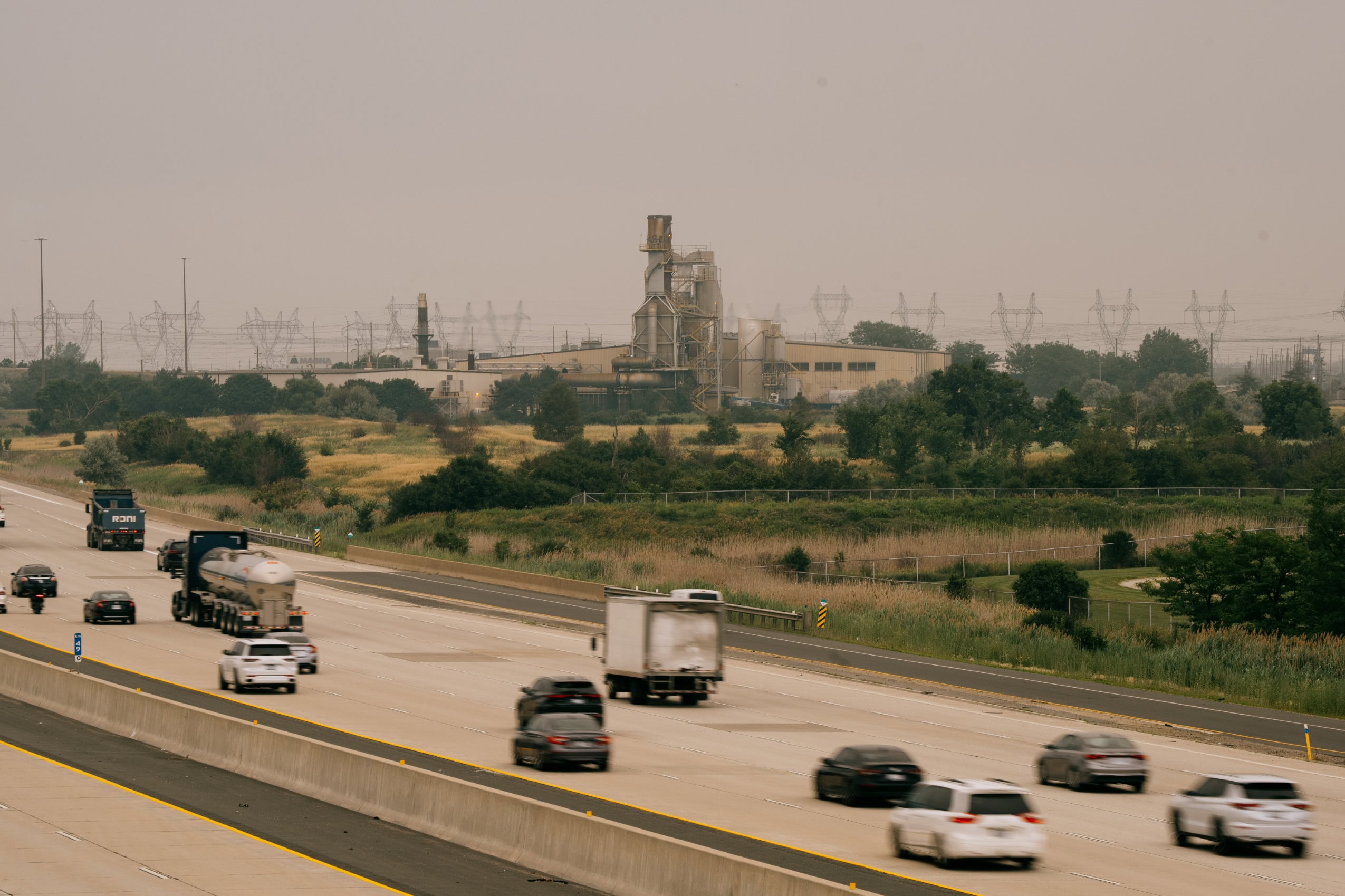 Cars drive the Emerald Energy from Waste incinerator on a hazy day in Brampton, Ontario.