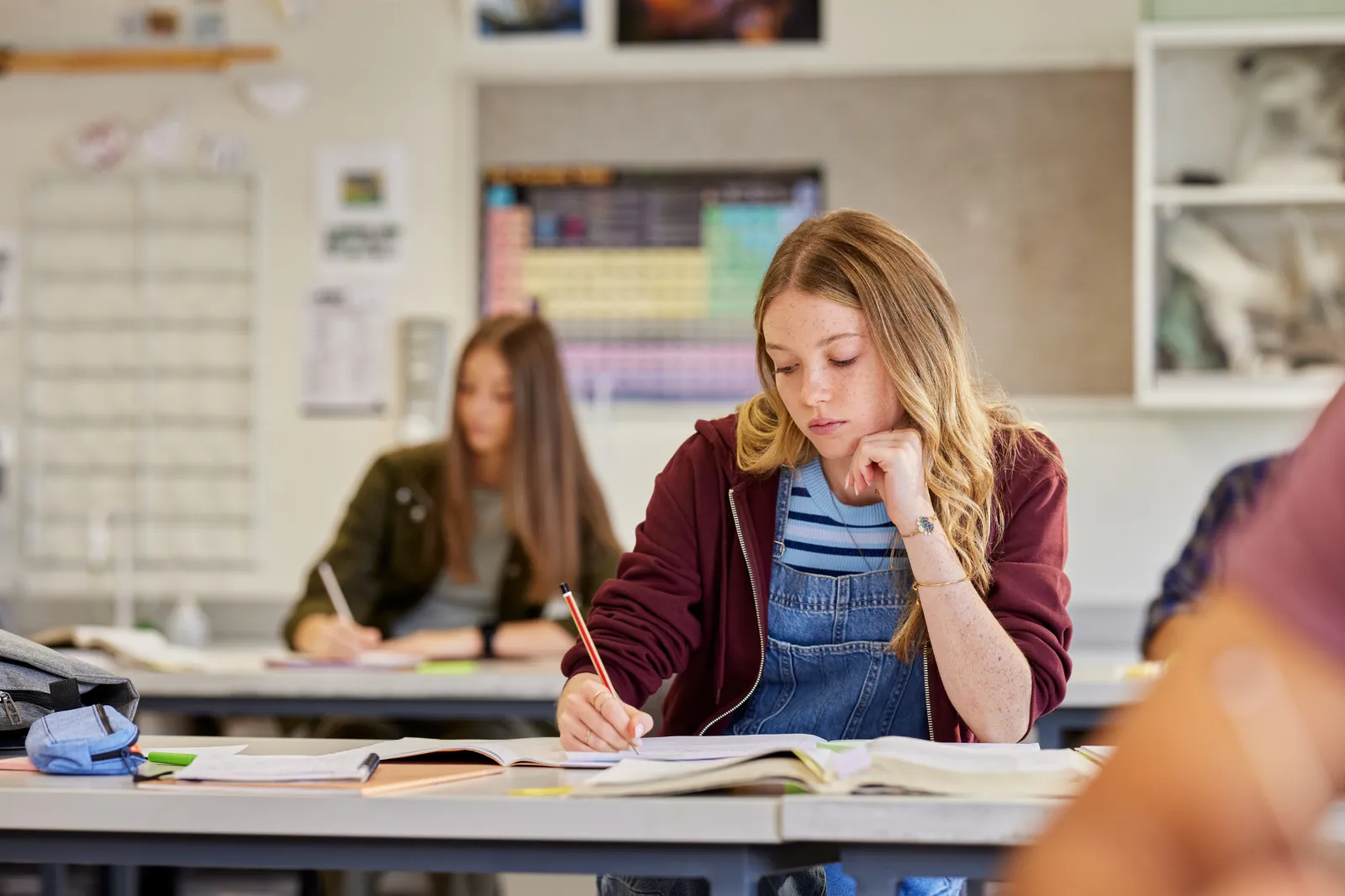 Stock image: a bored female student writes in her notebook during a lesson.