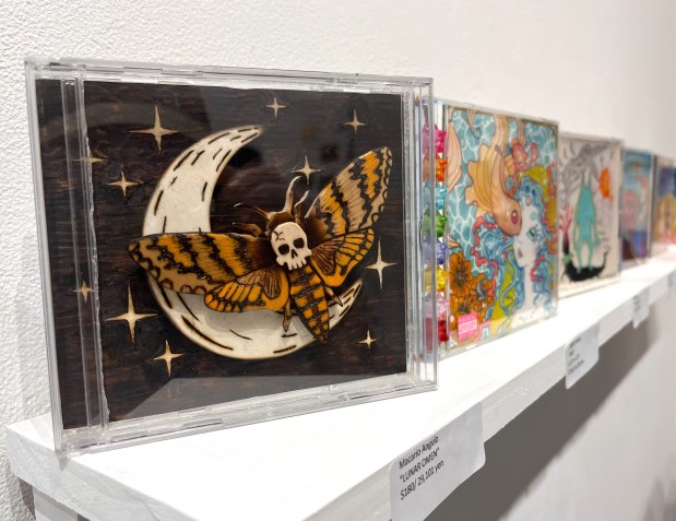 The traveling exhibit "UltraHive 4" is on view until Sept. 26, 2026, at the FM Oakland art gallery in Oakland, Calif. It features more than 100 artists designing their own CD-case covers. Pictured: "Lunar Omen" by Macario Angulo. (John Metcalfe/Bay Area News Group)