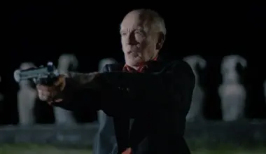 John Malkovich stars as veteran CIA officer Chris shooting a gun on Eastern Island in the action-thriller WILD HORSE NINE directed by Martin McDonagh.