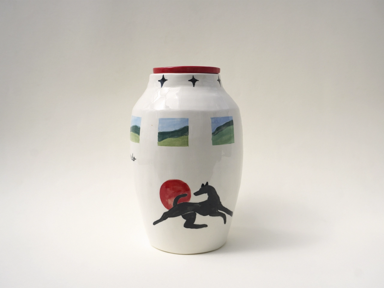 White ceramic vessel decorated with a black silhouette of a leaping horse, red circle, landscape vignettes and geometric stars