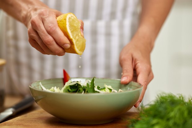 Stock image of a lemon being squeezed over a salad