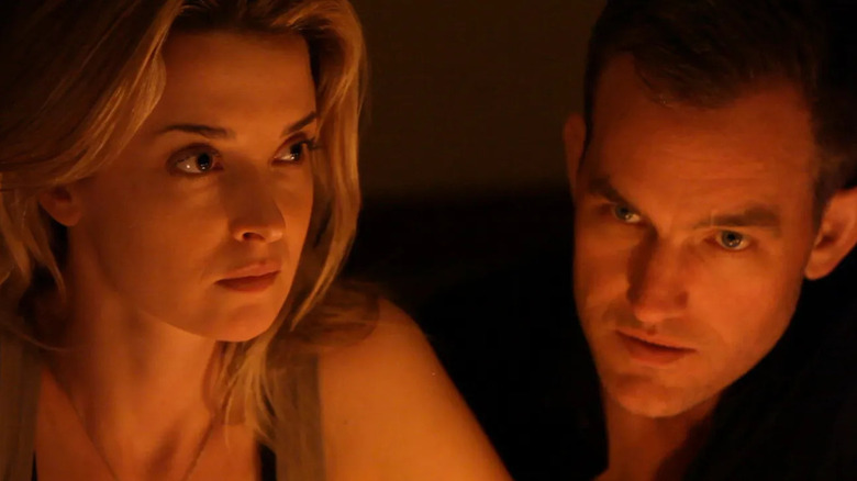 A medium shot of Emily Baldoni as Emily and Maury Sterling as Kevin in Coherence, sitting next to each other.