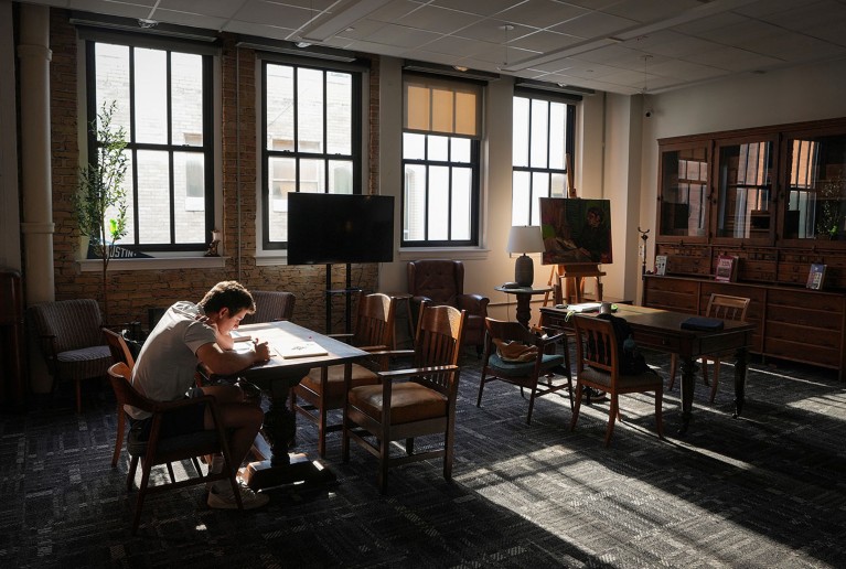 A student studies alone in an empty university library.