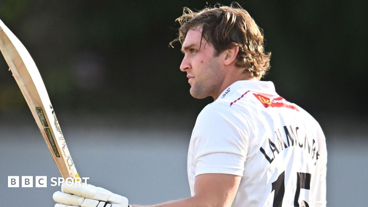 Tom Lammonby raises his bat in his left hand with his helmet off and in his right hand after passing 100 for Somerset