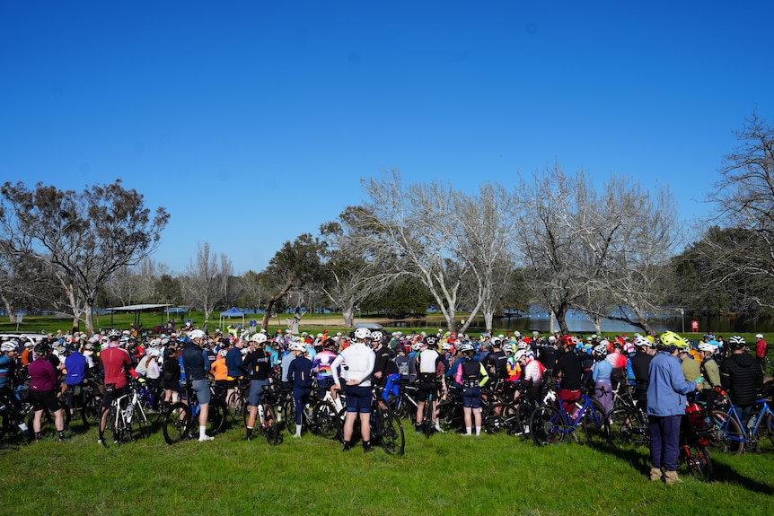 A crowd of cyclists standing together outside.