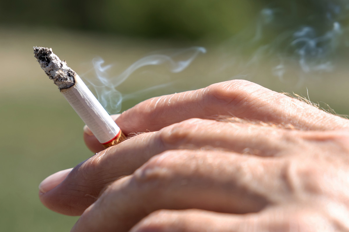 Human hand holds smoking cigarette