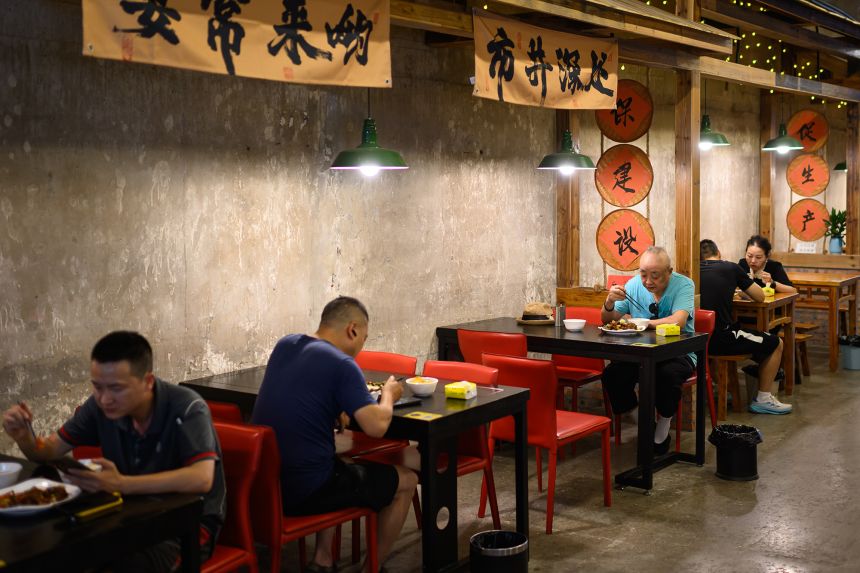 Men dine alone at the Shancheng Memory Underground City Community Canteen in Chongqing, China, on August 13, 2026.