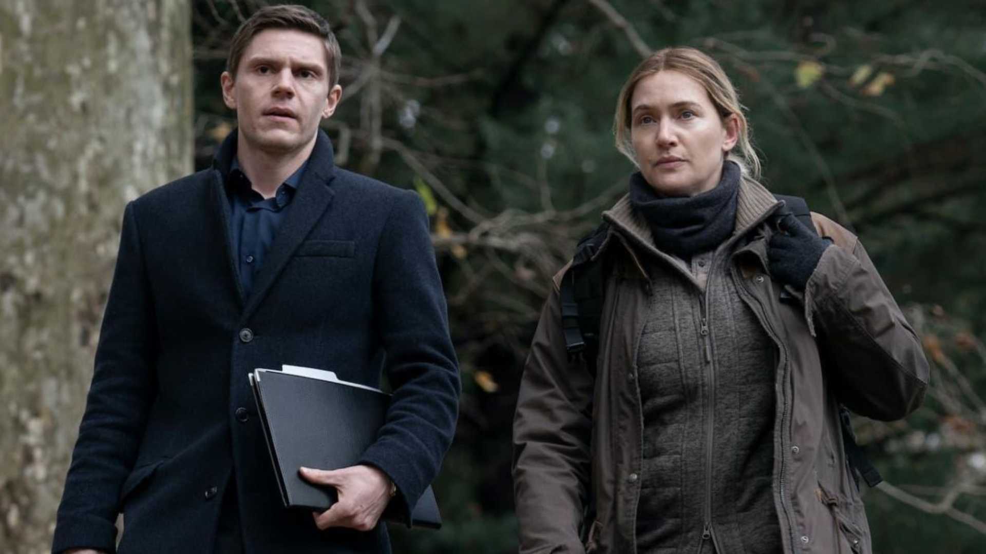 Kate Winslet and Evan Peters in Mare of Easttown walking near a forest