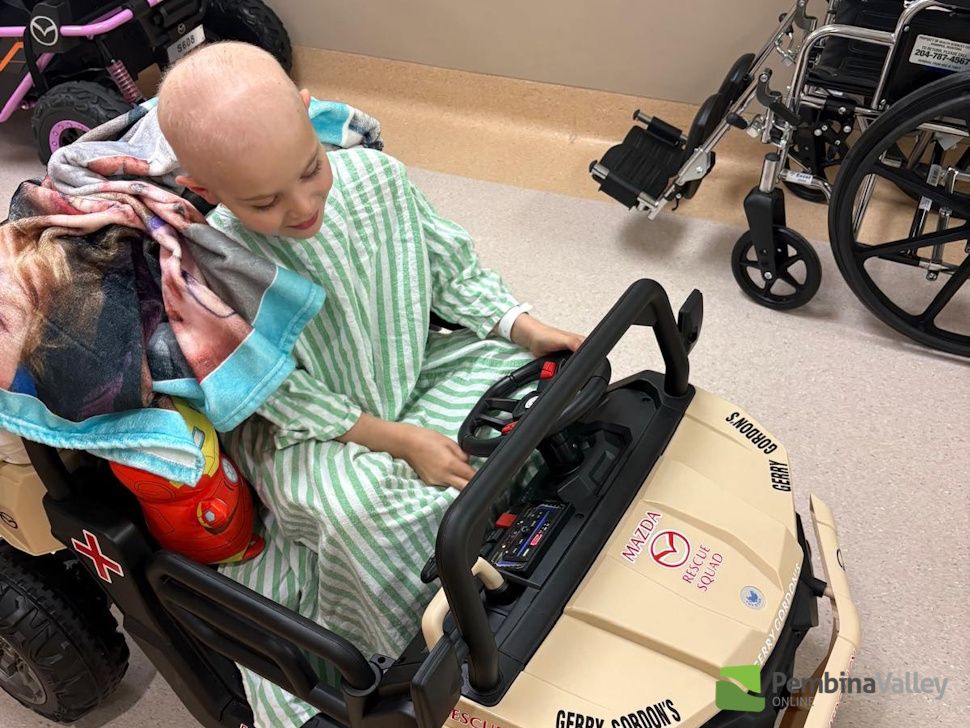 Maverick riding a small child's car in the hospital