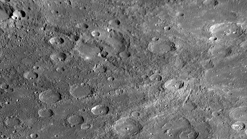 A long cliff face runs through a large ancient crater on Mercury's scarred surface.
