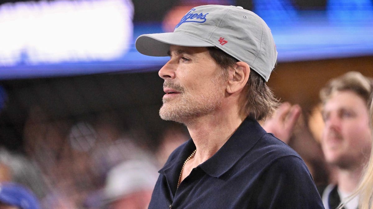 Rob Lowe seated in the stands at a baseball game.