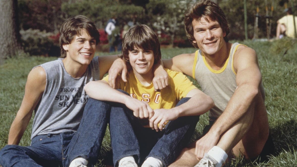 Rob Lowe, C. Thomas Howell and Patrick Swayze stand on the set of The Outsiders.