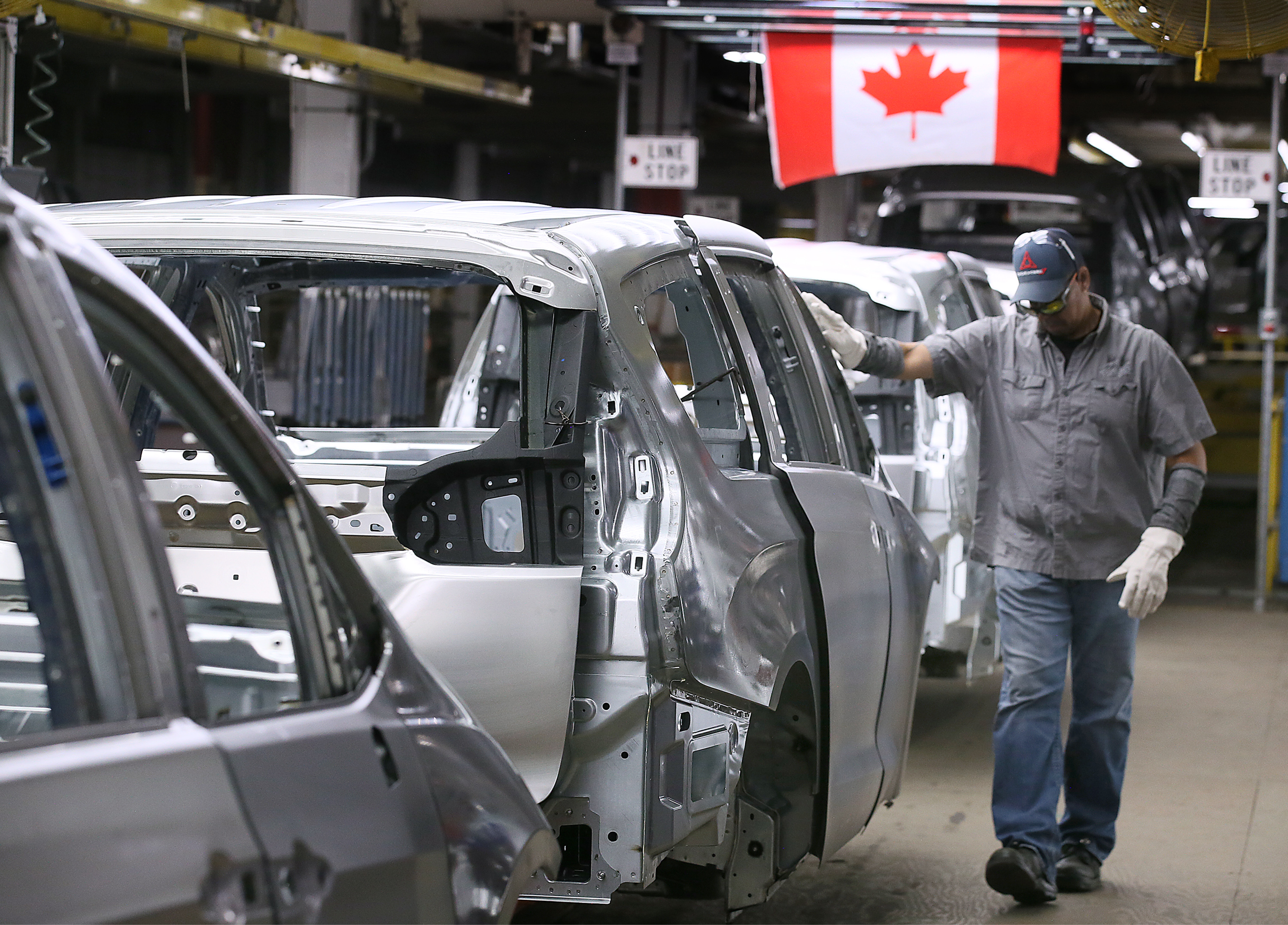a car's frame in an assembly line with Canadian flag in the background