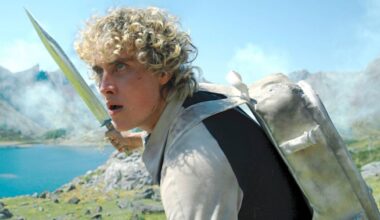 young man with curly blonde hair holding a weapon in an outdoor arena