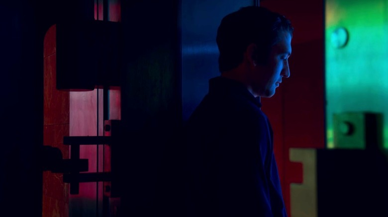 Martin standing under blue neon lighting and looking down on Too Old to Die Young S1E3