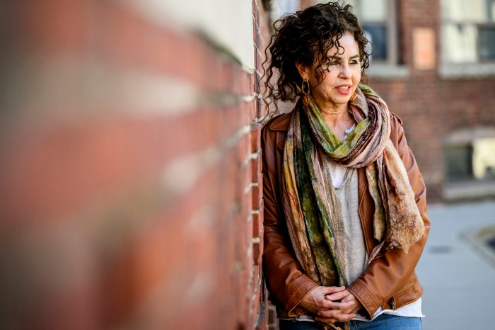 Northeastern psychology professor Iris Berent stands by a brick wall, hands clasped, wearing a scarf and leather jacket outdoors