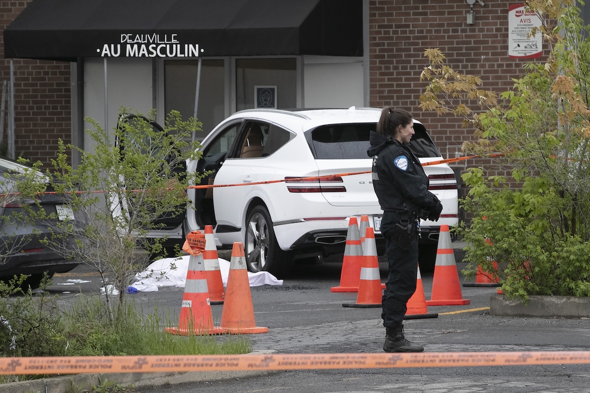 Montreal police stand near the body of Claudia Iacono near a car with projectiles holes in side window.