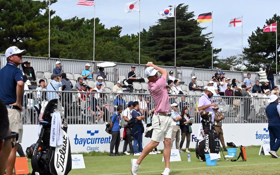 A golfer swings an iron on a driving range during a tournament practice session.