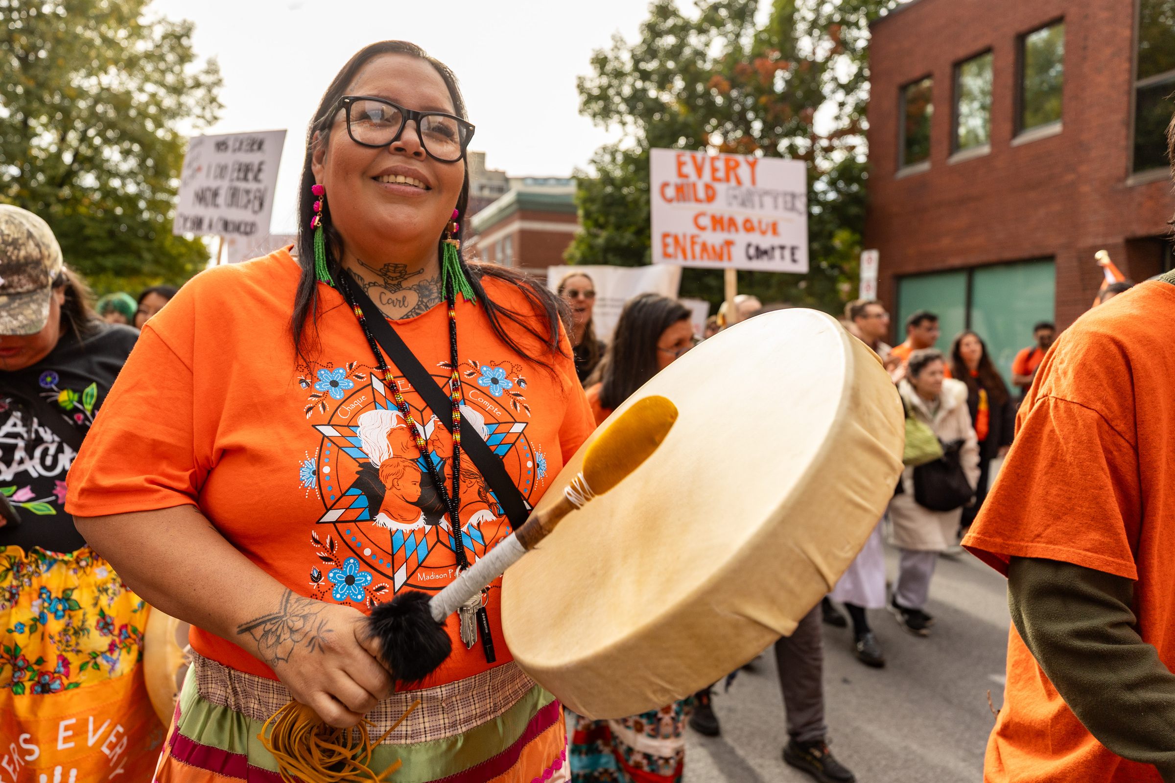 Jamie Starr plays a drum while wearing orange.