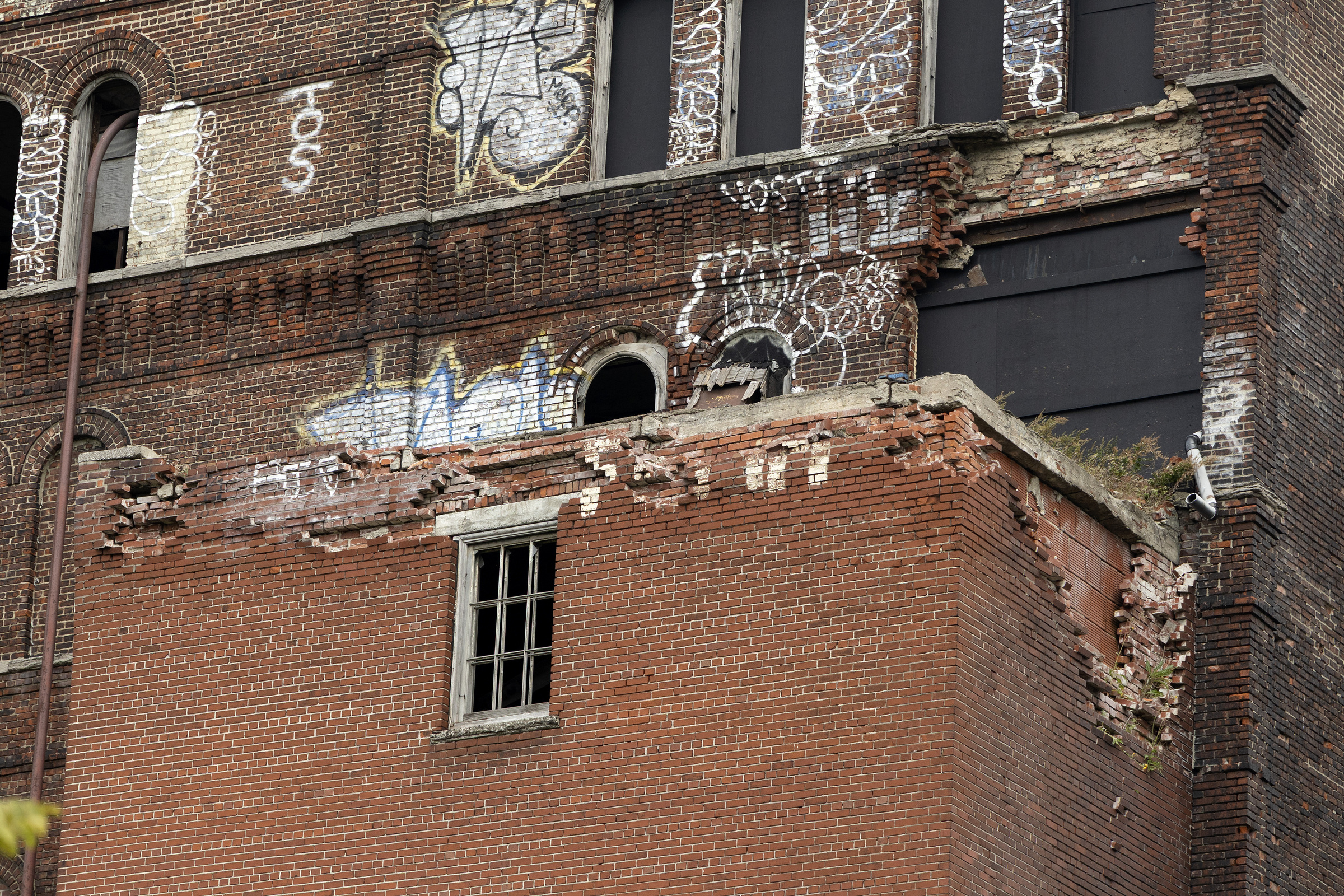 A closeup of partly collapsed brick walls on the exterior of a large building.