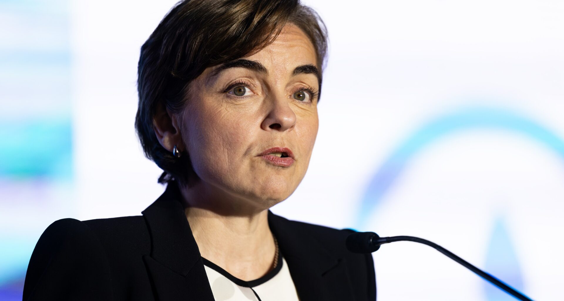 A woman speaks into microphone on stage.