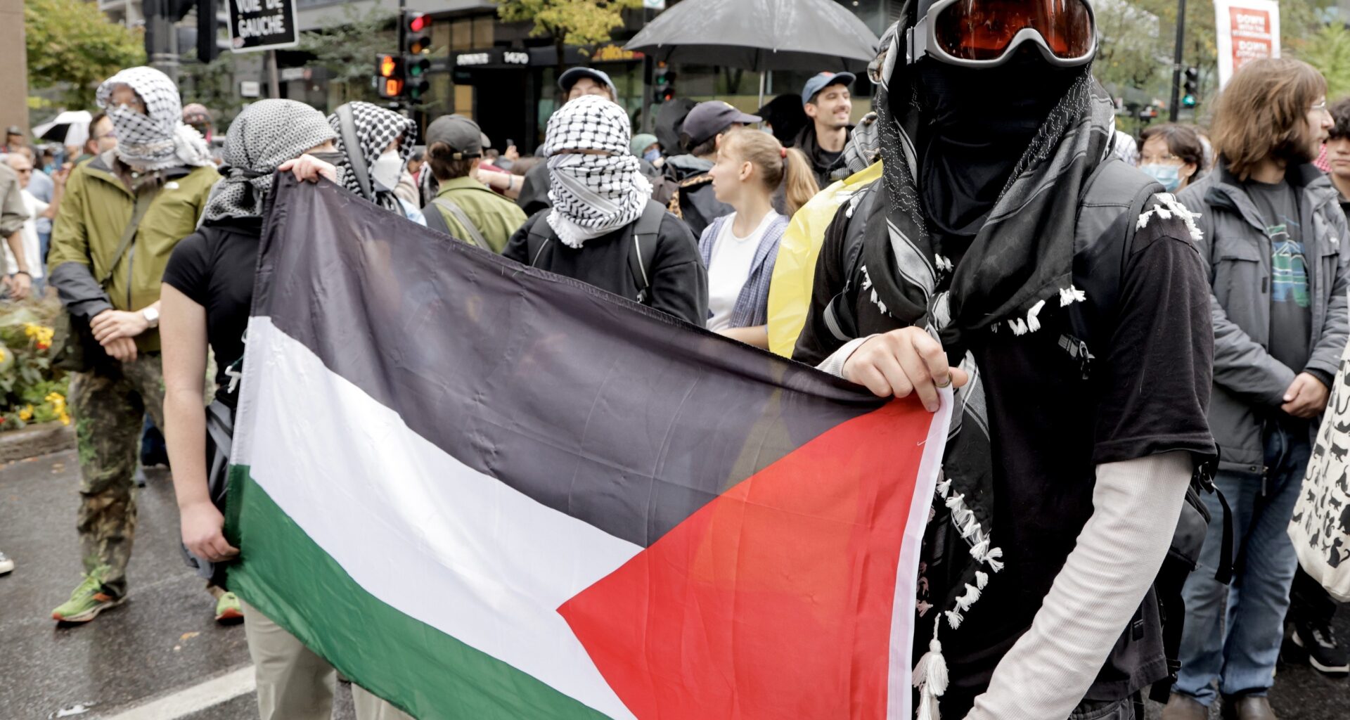 Masked protesters hold a Palestinian flag during a rally on the streets of Montreal on Oct. 7, 2025